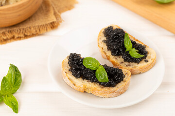 Bread slice with black caviar served on on wooden table