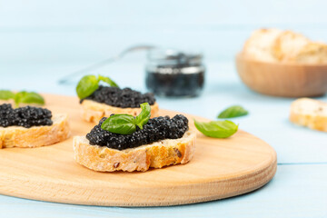 Bread slice with black caviar served on on wooden table