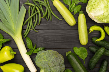 Different fresh green vegetables on wooden background, top view