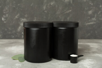 Jar with protein powder on concrete background. Sports nutrition concept