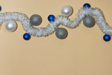 Holiday tinsel with blue and silver balls on beige background