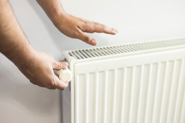 Man adjusting temperature on heating radiator