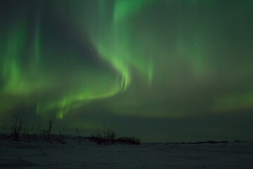 Aurora Borealis over a river valley. Night winter arctic landscape. Snow-covered frozen river in...