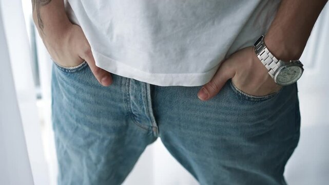 A man tries on pants in a fitting room in a store.
Hands in pockets.
Pants with pockets.
A man hides his hands in his trouser pockets.
Denim pants