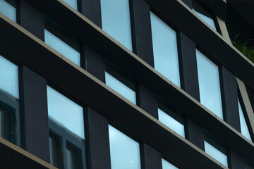 This modern architectural structure showcases an array of elegantly arranged windows set against a vibrant urban background