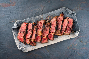 Traditional barbecue dry aged Wagyu rib eye beef steak with salt and pepper sliced and served as...