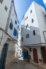 Fototapeta premium narrow, winding alleyway in a traditional Moroccan medina, with whitewashed buildings, colorful doors, and intricate architectural details, creating a picturesque and authentic scene