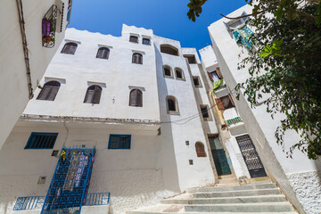 Fototapeta premium narrow street ascending between whitewashed buildings with colorful accents, creating a picturesque and characteristic scene in a Mediterranean town