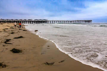 A pier is visible in the distance, with a beach in the foreground