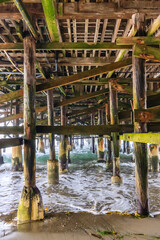 A pier with wooden posts and a greenish-brown color
