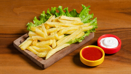 French fries on wooden tray with ketchup and mayonnaise