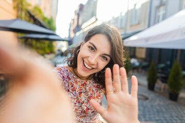 POV view of young woman blogger taking selfie on smartphone, communicating video call online with subscribers, recording stories for social media vlog outdoors. Adult girl walking in urban city street