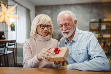 senior husband give gift box with red ribbon to her senior wife