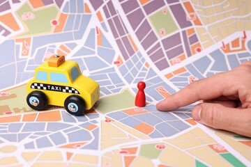 Woman pointing at city map with yellow taxi car and human figure, closeup