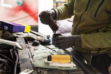 Auto mechanic is changing old dirty oil filter in BMW