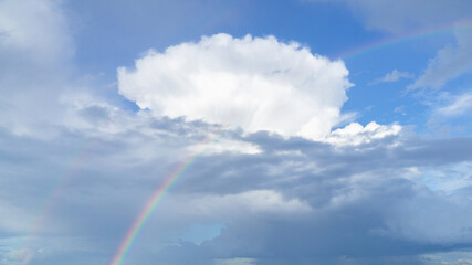 Bright rainbow against a beautiful huge cloud dramatic sky. Atmospheric phenomena.