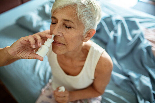 Senior woman using nasal spray for allergies or congestion