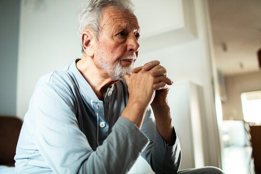 Thoughtful senior man sitting at home in pajamas