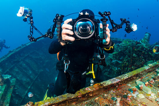 Underwater photographer with large camera on a large underwater shipwreck on a coral reef (Boga, Tulamben, Bali)