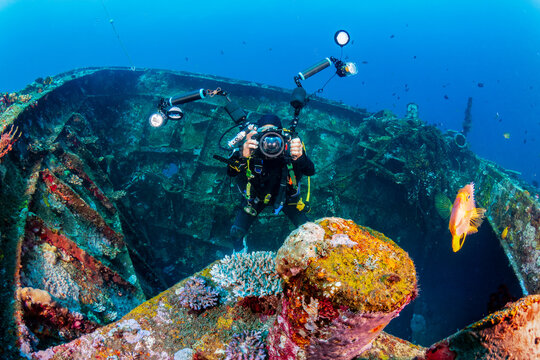 Underwater photographer with large camera on a large underwater shipwreck on a coral reef (Boga, Tulamben, Bali)