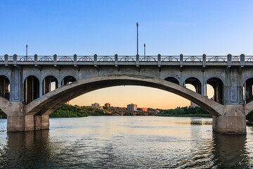 Fototapeta premium A bridge spans a river with a city in the background