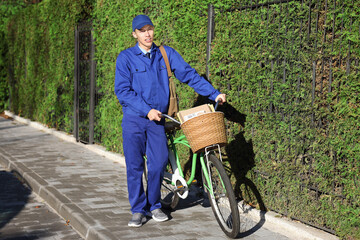 Postman with parcels in bicycle basket outdoors