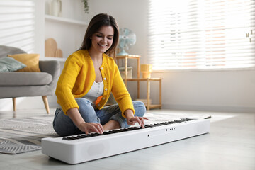 Smiling woman playing synthesizer on floor at home
