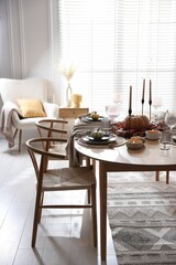 Stylish table setting with beautiful dishware and autumn decor in dining room