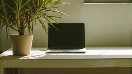 Fototapeta premium The open laptop with a blank screen rests on a wooden table, ready for work in vintage room design