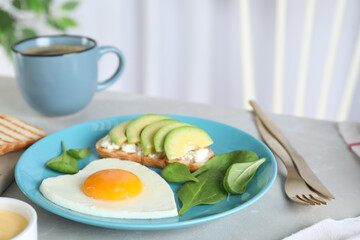 Romantic breakfast with heart shaped fried egg served on light grey kitchen table