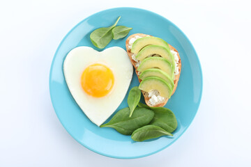 Plate of tasty breakfast with heart shaped fried egg isolated on white, top view