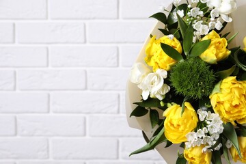 Beautiful bouquet with peony tulips near white brick wall, closeup. Space for text