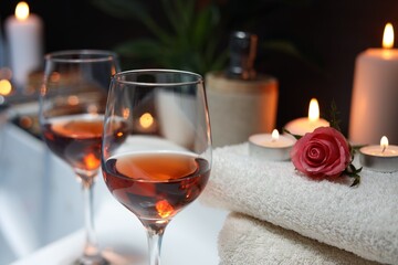 Wine in glasses and rose on edge of bath indoors, closeup. Romantic atmosphere