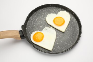 Heart shaped fried eggs in frying pan isolated on white
