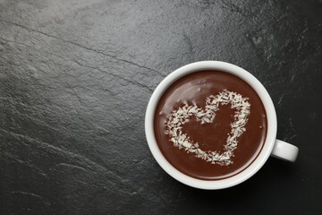 Cup of hot chocolate with heart shaped decoration on black table, top view. Space for text
