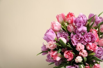 Beautiful bouquet of colorful tulip flowers on beige background, top view. Space for text
