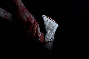 Man holding bloody axe in darkness, closeup
