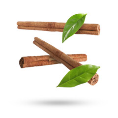 Cinnamon sticks and green leaves in air on white background