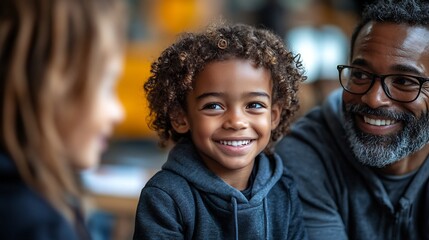 Parents teachers discussing a students progress in a school meeting with the child sitting proudly between them smiling at the praise