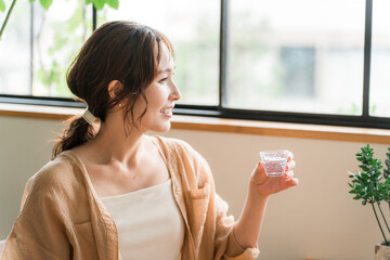 冷酒グラスで日本酒を飲む若いアジア人女性
