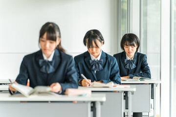 学校の教室で真剣に授業を受ける制服姿の小学生・中学生・高校生・女子高生（友達）
