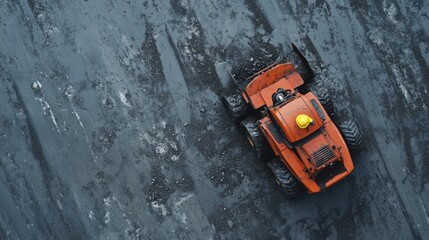 Aerial view of an orange tractor on dark terrain.