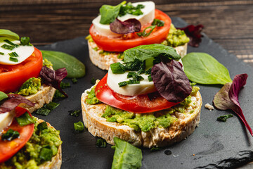 Vegan food, rice cakes with avocado mozzarella spinach onion on a stone board