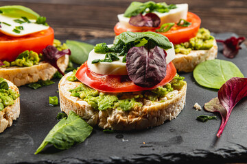 Rice cakes with mozzarella, avocado, spinach, onion on a stone on a wooden table