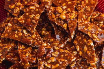 Homemade sweet gozinak with various nuts on a red plate, Christmas concept