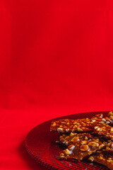 Homemade sweet gozinak with various nuts on a red plate, Christmas concept