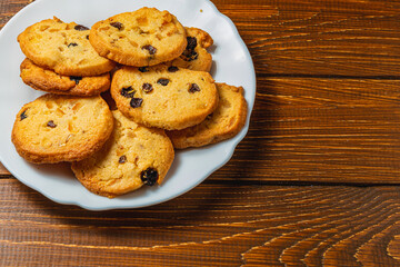 Delicious Christmas cookies with raisins on a white plate on a wooden table