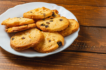 Delicious Christmas cookies with raisins on a white plate on a wooden table