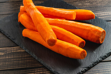 Washed fresh carrots on a stone board on a wooden table