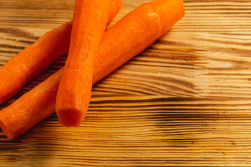 Washed fresh carrots on a light wooden board